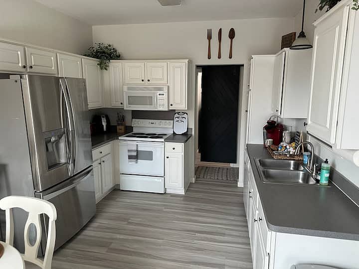 Kitchen with white cabinets, stainless refrigerator, stove, microwave, and double sink
