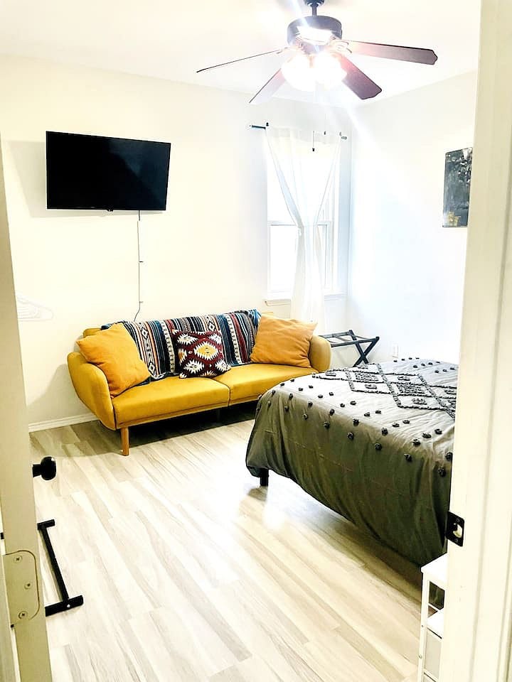 Third bedroom with a full bed, yellow sofa, and TV
